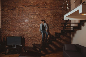 A full length portrait of a handsome stylish man posing in loft studio interior. Fashion for men. © Alexandr