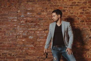 Portrait of a handsome stylish man posing in loft studio interior. Fashion for men.