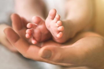 Dad holding the feet of a newborn baby. Selective focus