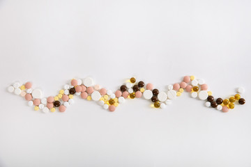 pills are on a white background, drugs of different colors are located along the length of the frame, drugs are laid out creatively