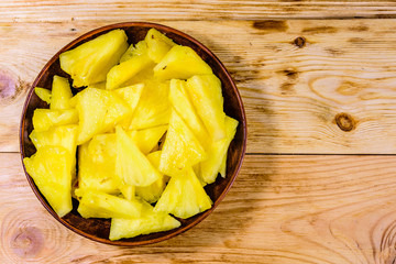 Ceramic plate with sliced pineapple on wooden table. Top view