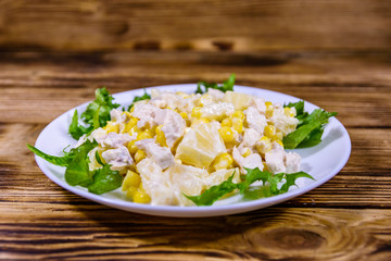 Festive salad with chicken breast, canned pineapple, cheese, sweet corn and mayonnaise on wooden table