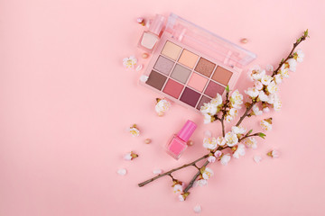 Cosmetics and Sakura branch on a pink background. Beauty concept, flat lay.