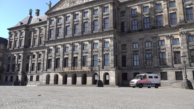 Police car on empty Dam Square in Amsterdam during corona virus outbreak and partial lockdown of Dutch society