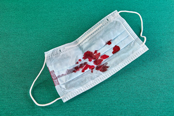 Used disposable face mask with blood stains.