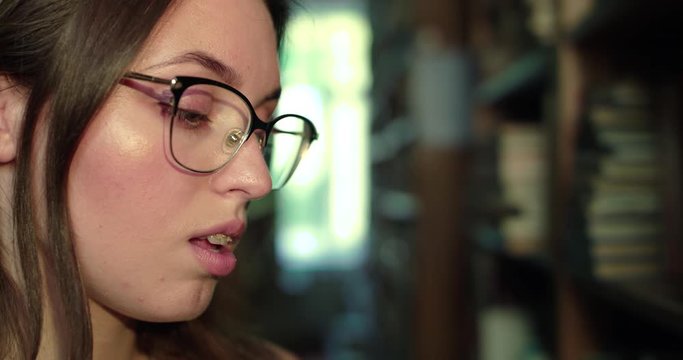 Close profile of girl in glasses leading the eyes during reading in lirbary