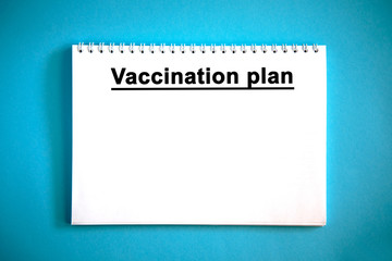 VACCINATION PLAN - text on a white notebook on a blue background