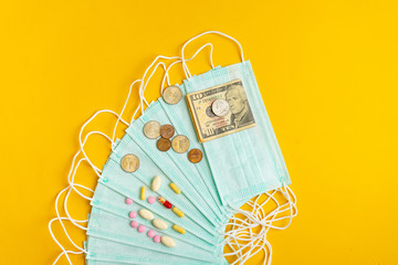 Sale of medical masks. Protective medical mask and different types of pills next to money on yellow background. Coronavirus concept. 2019 nCoV