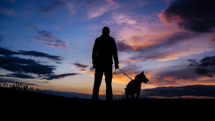 Silhouette of a hunter with a dog at sunset - Powered by Adobe