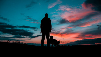 Silhouette Of Young Man With Dog At Sunset