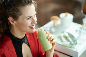 woman at modern home in sunny day drinking bottle of smoothie