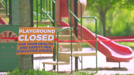 Children's playground closed off with caution take due to coronavirus with sign saying playground closed due to executive order - Powered by Adobe
