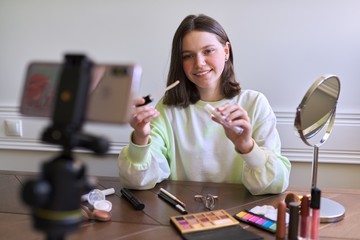 Teenage girl, beauty blogger filming video for her channel, blog, showing lip gloss