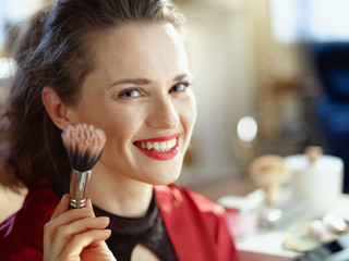 smiling woman in modern house in sunny day using cosmetic brush