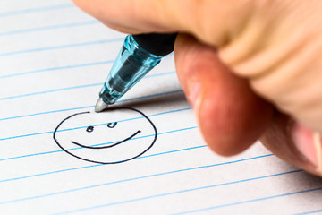 Drawing a smiley face with a pen onto a piece of paper - 344337657