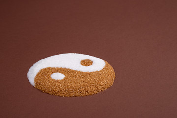 Yin yang symbol made with refined white sugar and cane sugar. Visual metaphor comparing both...