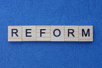 text on gray word reform of small wooden  letters lies on a blue  table