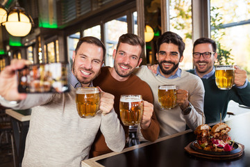 Happy friends make selfie in beer pub