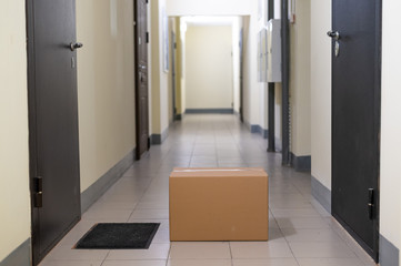 Contactless door delivery concept. Cardboard box with online purchase at the front door in the...