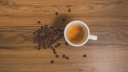 Cup of coffee with coffee grains in a wood background