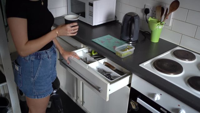 Young woman with artificial leg with coffee cup in kitchen at home