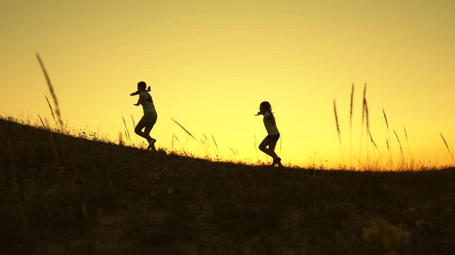 Children on background of sun with an airplane in hand. Dreams of flying. Happy childhood concept. Two girls play with a toy plane at sunset. Silhouette of children playing on plane