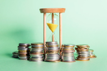 Lots of coins, hourglass, green background
