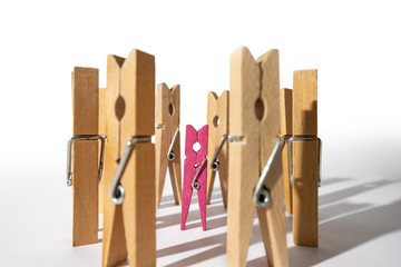Conceptual composition of clothespins simulating a girl surrounded by people. Scene of bullying and harassment towards the different and weak person.