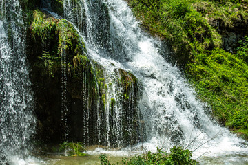 Beaumes-les-Messieurs tuffs waterfall. Cave and Rock covered with moss in a natural site. Jura -...