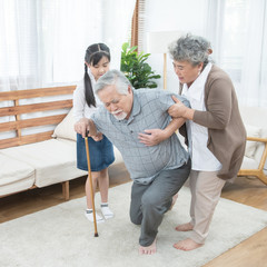 Asian grandfather fall down grandmother and granddaughter help and support carry him to sit on sofa,retirement life concept.