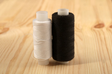 Spools of white and black natural thread on a wooden table. Sewing Accessories