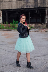 Portrait of a young girl with pink hair standing outside of collapsed building