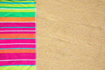 Beach towel photographed from above on sandy beach with copy space, hot summer day, vacation destination