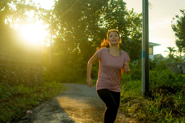 outdoors running workout - young happy and dedicated Asian Chinese woman jogging at beautiful city park or countryside trail on sunset enjoying fitness and cardio activity