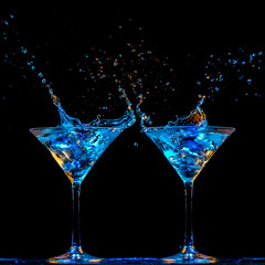 Dos copas de martini con líquido salpicando, centradas abajo sobre fondo negro.