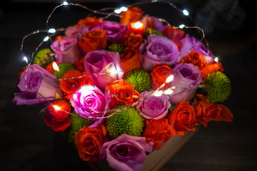 Top view of bunch or bouquet of roses with tiny lights in the box, gift for happy mother's day
