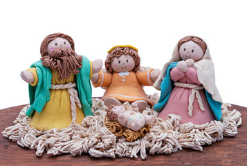 figures of the holy family as an ornament on a wooden base on white background, handcrafted nativity scene decoration for Christmas