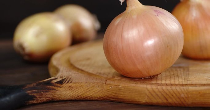 Onions in the husk on a wooden cutting Board.