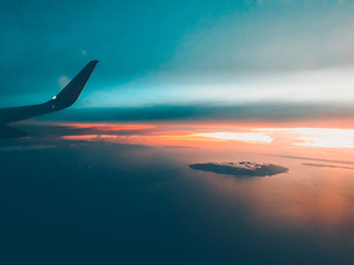 Naklejka na ściany i meble sunset over the sea while on an airplane.