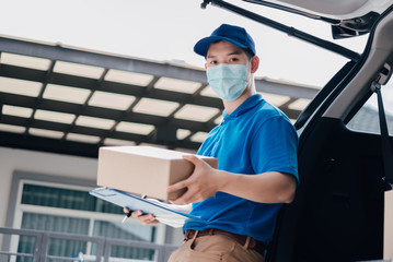 Asian Delivery man wearing mask picking up the package on front receiver shipping deliver cargo...