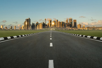 asphalt road in perspective view with urban cityscape in sunset, empty highway with skyline city...