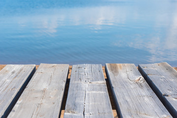 Close-up of picnic table with blue lake water in background on sunny day