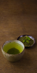 Japanese green tea in a bowl on a dark wooden table 