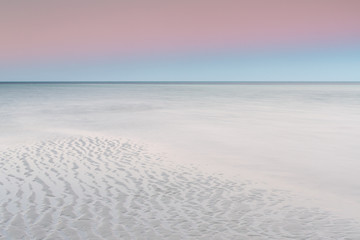 Fototapeta na wymiar white sandy beach with pastel sky at dawn