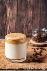 Dalgona coffee on a wooden background. A glass of trendy drink made from milk and whipped foam. Rustic style