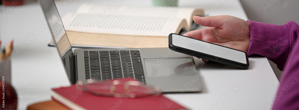 Poster side view of college student relaxing with mock-up smartphone while doing assignment