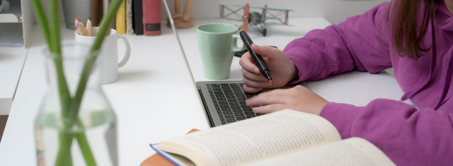 Close-up view of young girl studying on her final exam in comfortable room