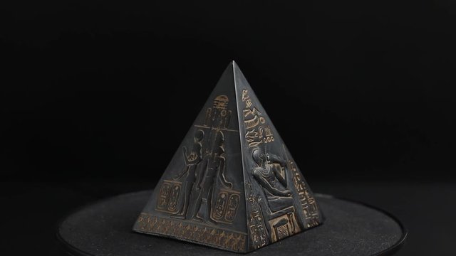 pyramid figure. pyramid figurine on a black background. the pyramid is spinning

