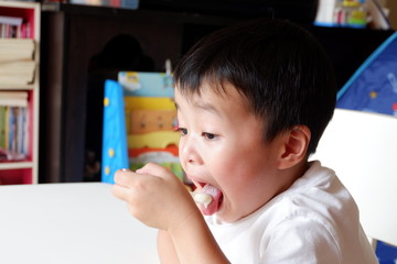 An Asian boy is eating snack and drinking water.
