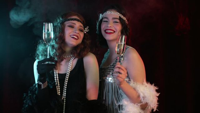 Beautiful flappers women dressed in style of Roaring twenties drinking champagne. Vintage, retro party, fashion, girls friends concept